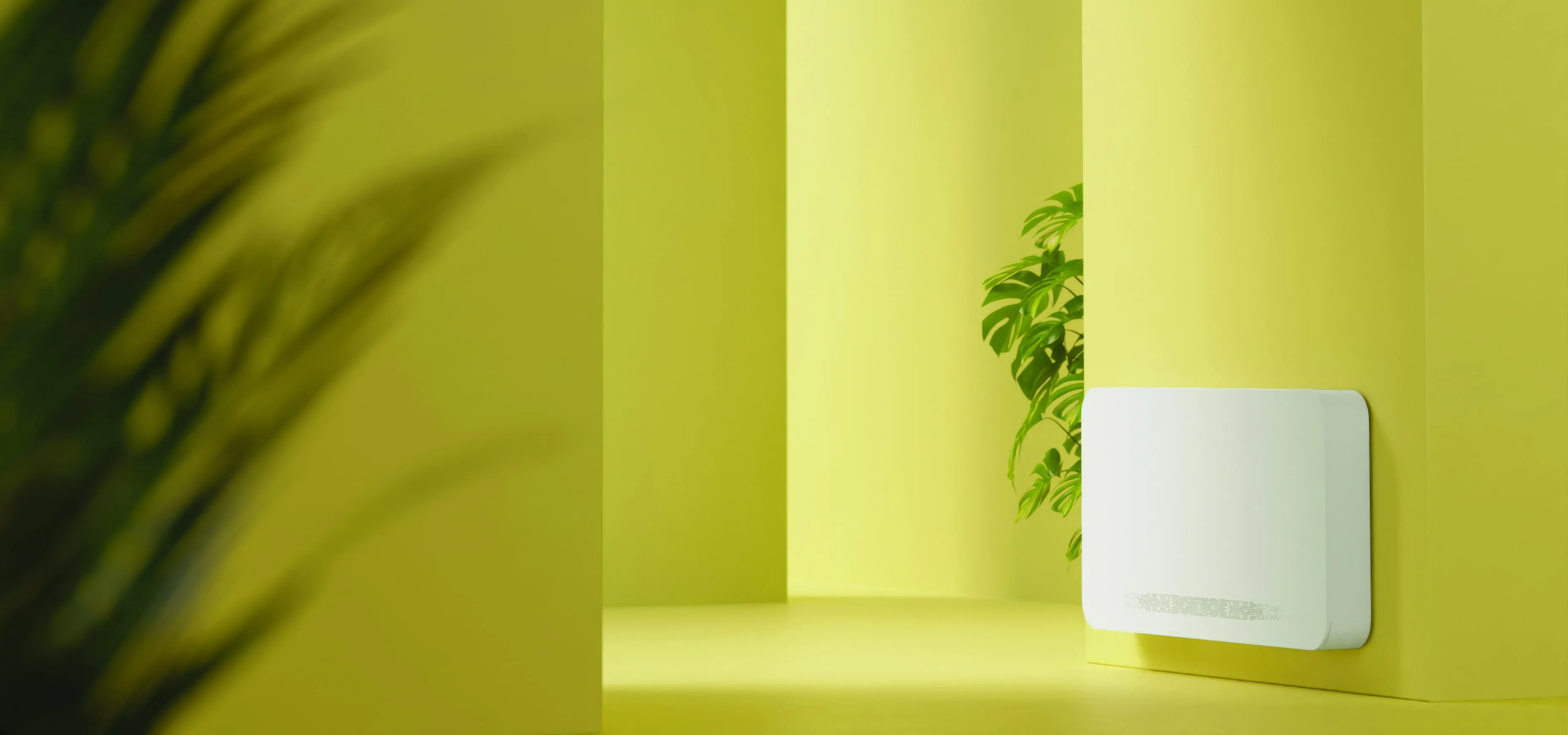 OSMO fan coil on a green wall beside a monstera